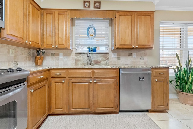 kitchen featuring appliances with stainless steel finishes, brown cabinetry, a sink, and ornamental molding