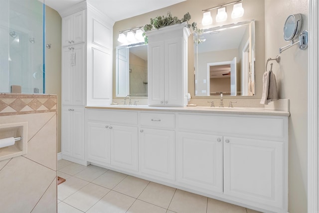 bathroom featuring a stall shower, double vanity, a sink, and tile patterned floors