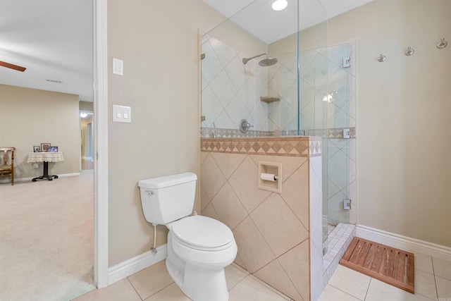 bathroom featuring tile patterned floors, baseboards, toilet, and a walk in shower