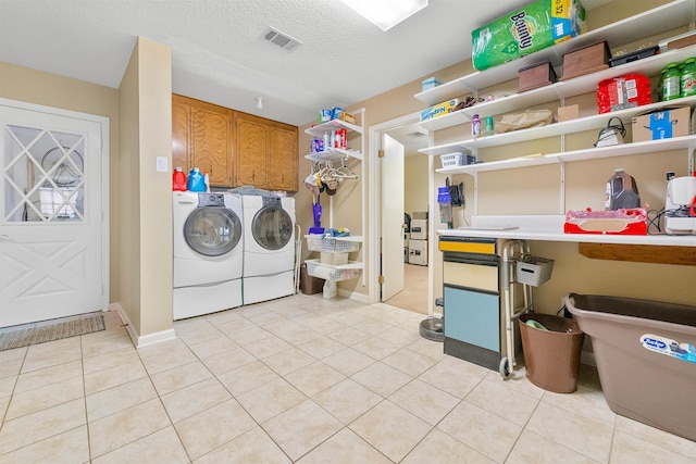 laundry area featuring cabinet space, light tile patterned floors, visible vents, and washer and clothes dryer