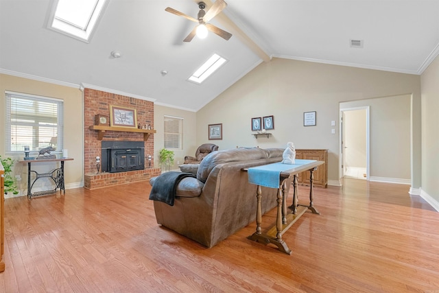 living room with vaulted ceiling with skylight, light wood-style flooring, visible vents, a ceiling fan, and ornamental molding