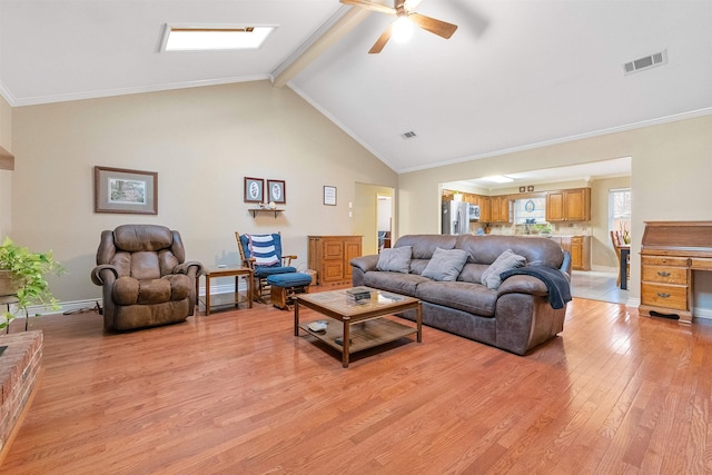 living room with a skylight, visible vents, ornamental molding, light wood-type flooring, and beamed ceiling