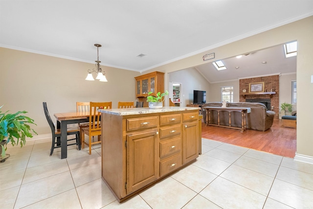 kitchen with a center island, brown cabinets, light tile patterned floors, hanging light fixtures, and glass insert cabinets