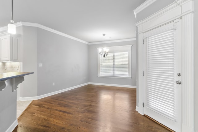 unfurnished dining area with a chandelier, dark wood-type flooring, baseboards, and crown molding