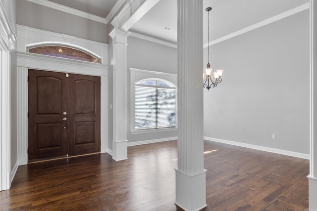 entrance foyer with a notable chandelier, dark wood-style flooring, baseboards, decorative columns, and crown molding