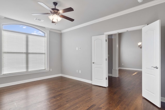 empty room featuring visible vents, dark wood-type flooring, ornamental molding, ceiling fan, and baseboards