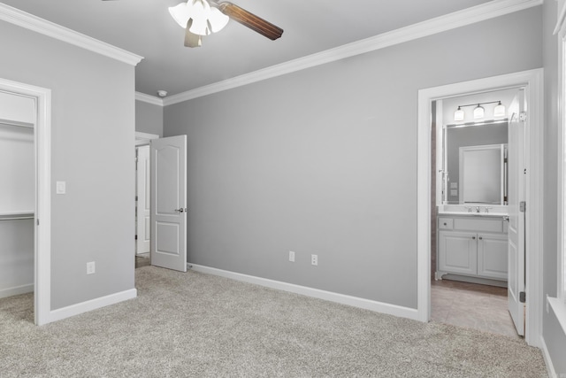 unfurnished bedroom with baseboards, light colored carpet, a spacious closet, crown molding, and a closet