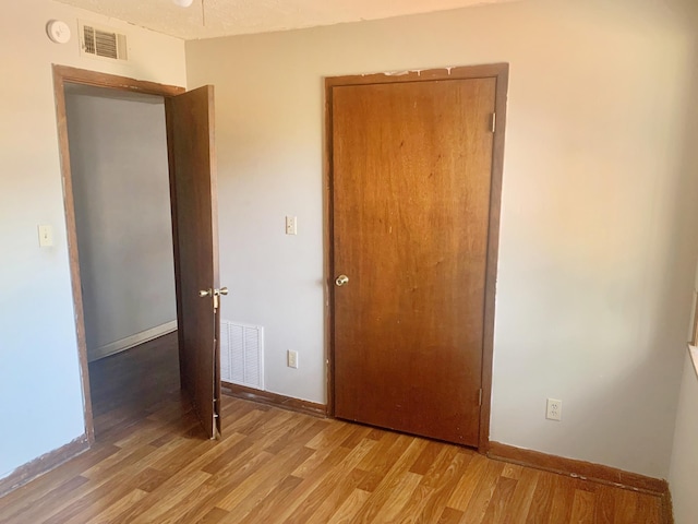 unfurnished bedroom with light wood-type flooring, visible vents, and baseboards