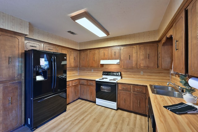 kitchen with visible vents, under cabinet range hood, light wood-type flooring, black appliances, and a sink