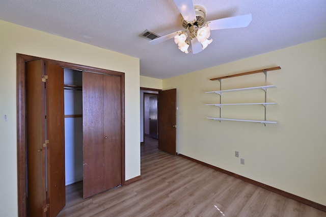 unfurnished bedroom with light wood finished floors, baseboards, visible vents, a textured ceiling, and a closet