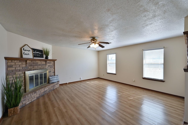 unfurnished living room with ceiling fan, light wood-type flooring, a fireplace, and baseboards