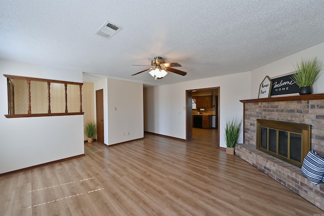 unfurnished living room featuring visible vents, a ceiling fan, a brick fireplace, wood finished floors, and baseboards