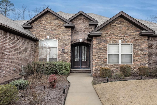 doorway to property with french doors, brick siding, and roof with shingles