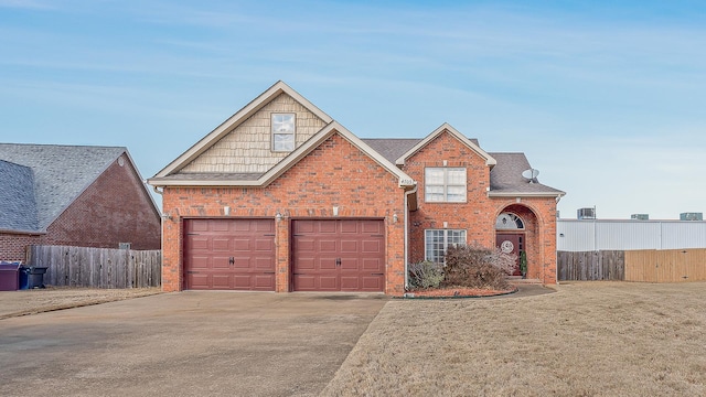 traditional-style home with concrete driveway, brick siding, an attached garage, and fence