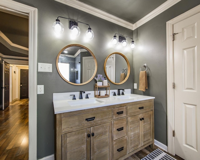 bathroom with a sink, crown molding, and wood finished floors