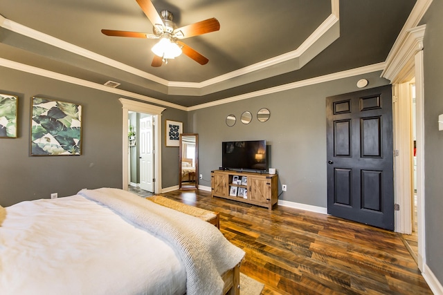 bedroom featuring a tray ceiling, dark wood-type flooring, visible vents, and crown molding