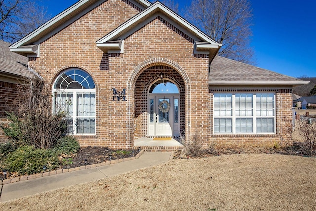 property entrance with brick siding and roof with shingles