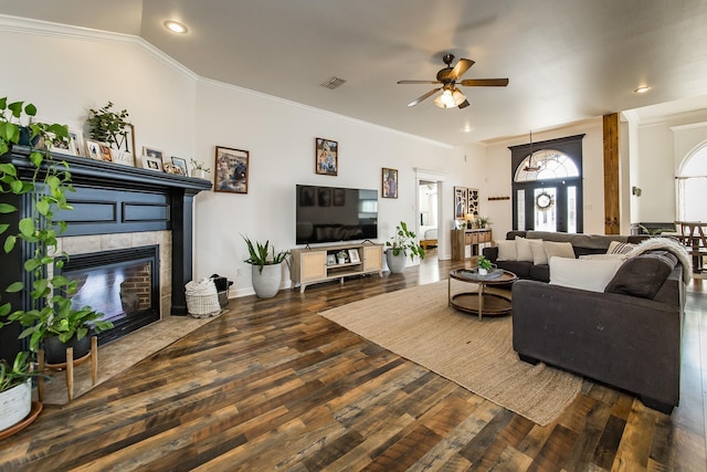 living area with a tile fireplace, dark wood finished floors, crown molding, and baseboards