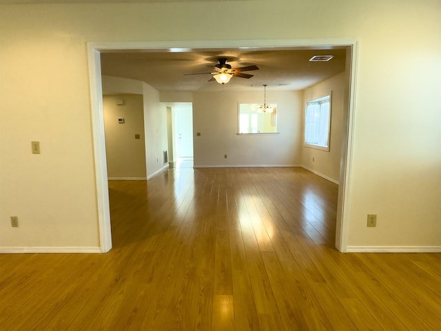 spare room with baseboards, visible vents, light wood finished floors, and ceiling fan with notable chandelier