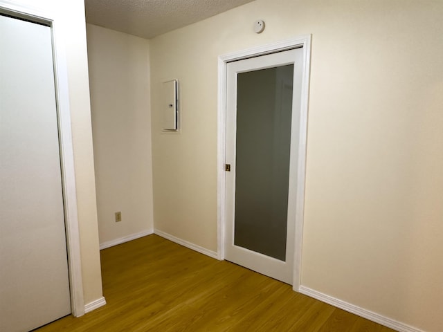 unfurnished room featuring light wood-style floors, baseboards, and a textured ceiling