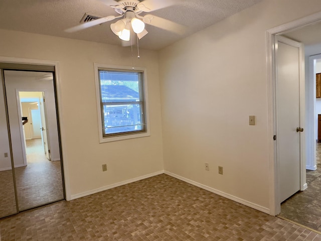 unfurnished bedroom featuring a ceiling fan, visible vents, baseboards, and a textured ceiling