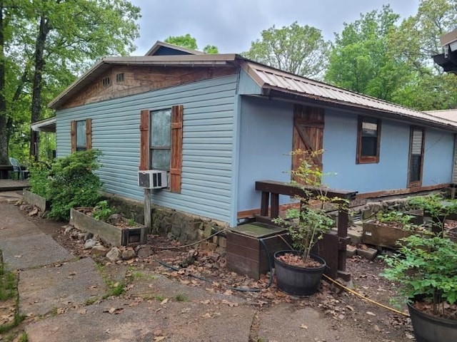 view of side of property featuring metal roof, cooling unit, and a garden