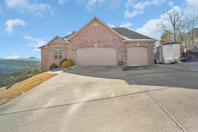 view of front of home with concrete driveway, brick siding, an attached garage, and a mountain view