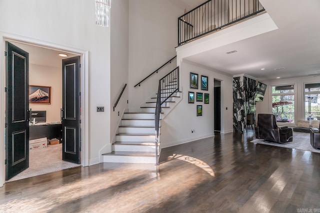 foyer featuring stairs, dark wood-type flooring, and a towering ceiling