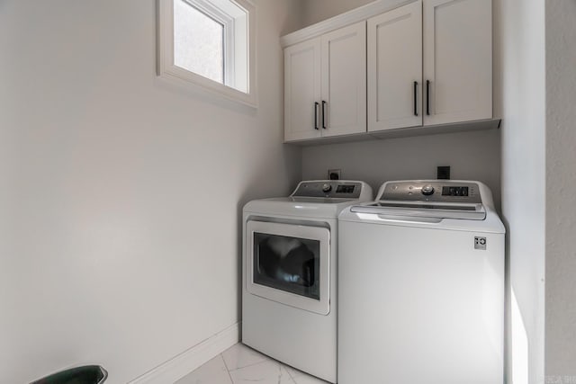 clothes washing area with washing machine and dryer, marble finish floor, cabinet space, and baseboards