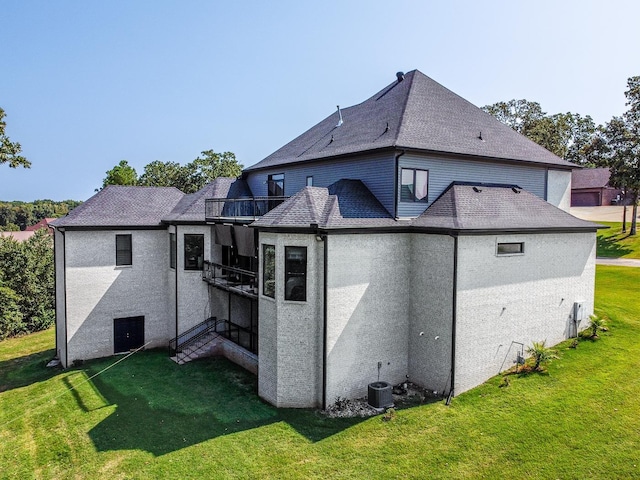 back of property with a balcony, stucco siding, central AC, and a yard