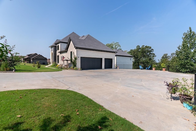 view of side of property featuring a yard, stucco siding, concrete driveway, an attached garage, and fence