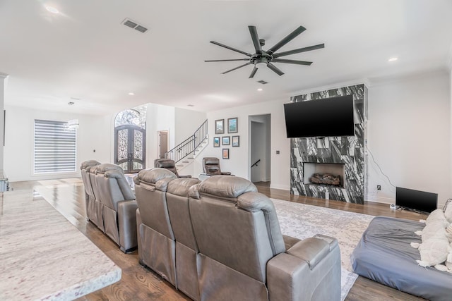 living room featuring stairs, a premium fireplace, wood finished floors, and visible vents