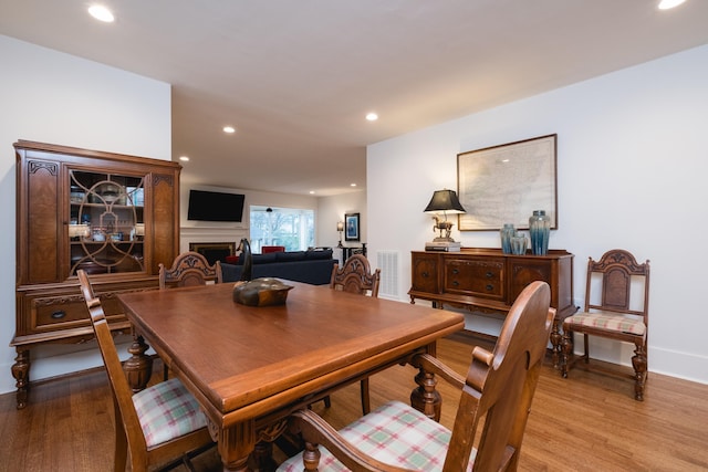 dining space featuring recessed lighting, a fireplace, visible vents, baseboards, and light wood-style floors