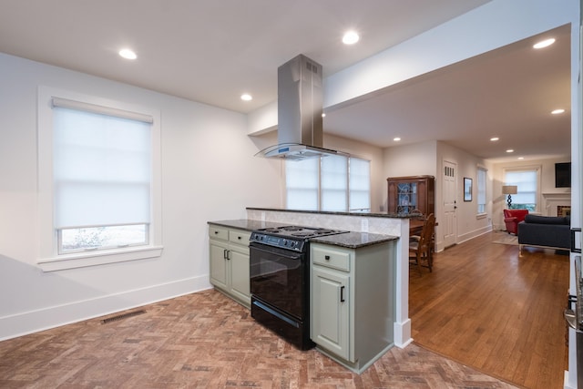 kitchen featuring island range hood, a peninsula, open floor plan, black electric range oven, and dark stone countertops