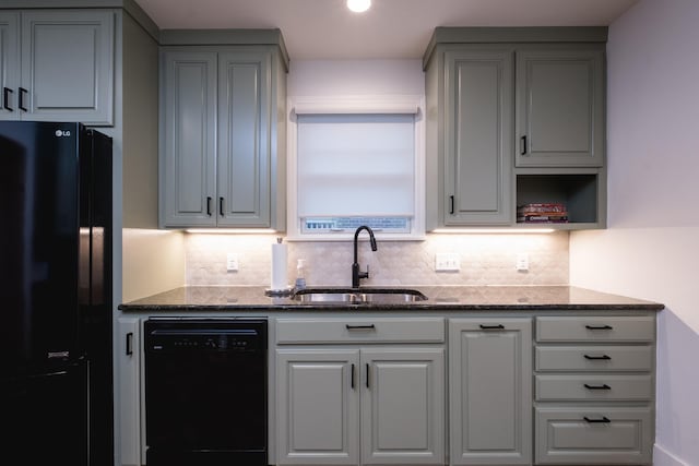 kitchen featuring dark stone counters, black appliances, a sink, and gray cabinetry