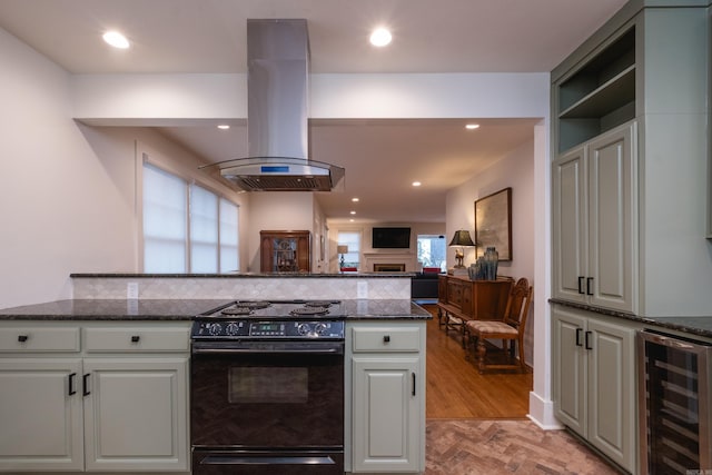 kitchen featuring wine cooler, dark stone countertops, island exhaust hood, and black electric range oven