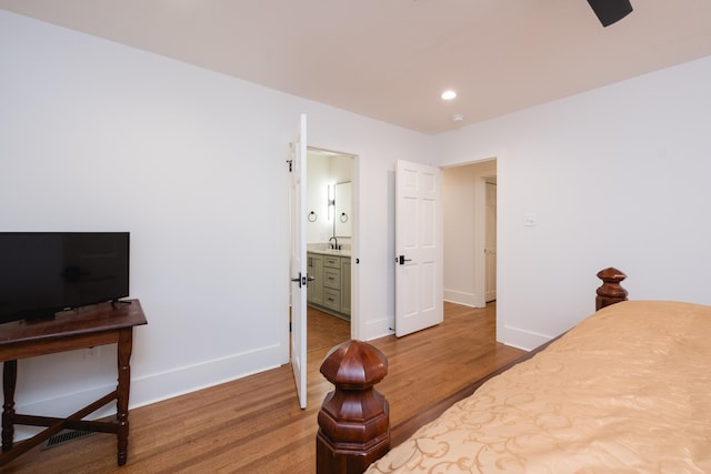 bedroom featuring a sink, wood finished floors, connected bathroom, and baseboards