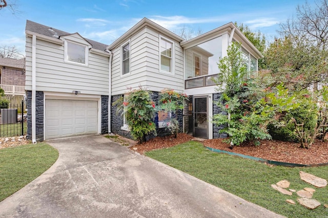 view of front of property featuring an attached garage, fence, stone siding, concrete driveway, and a front lawn