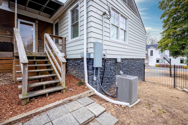 view of side of property with central air condition unit, fence, and stairway