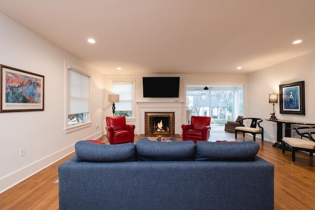 living area featuring light wood finished floors, a fireplace, recessed lighting, and baseboards