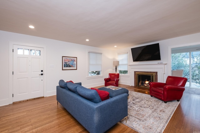 living area featuring recessed lighting, a fireplace, light wood-style flooring, and baseboards