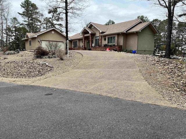 view of front facade with driveway, a shingled roof, a garage, and stucco siding