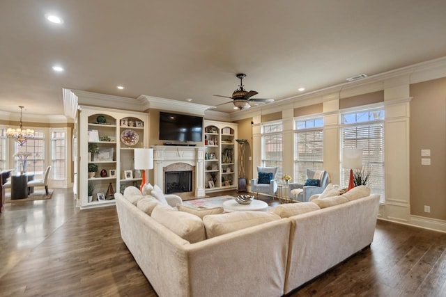 living area featuring crown molding, dark wood finished floors, a fireplace, visible vents, and ceiling fan with notable chandelier