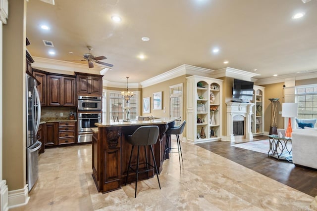 kitchen featuring an island with sink, open floor plan, a kitchen breakfast bar, hanging light fixtures, and a warming drawer