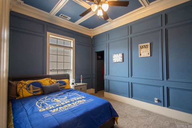 carpeted bedroom with visible vents, coffered ceiling, ceiling fan, ornamental molding, and a decorative wall