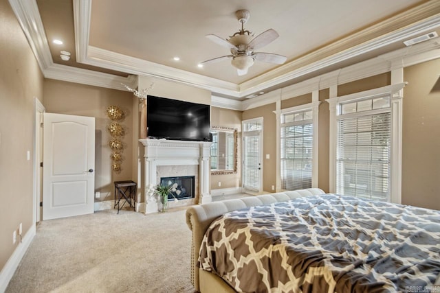 carpeted bedroom with baseboards, visible vents, a tray ceiling, a fireplace, and recessed lighting