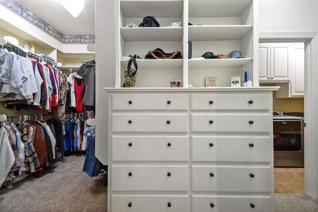 walk in closet with washer / clothes dryer and light colored carpet