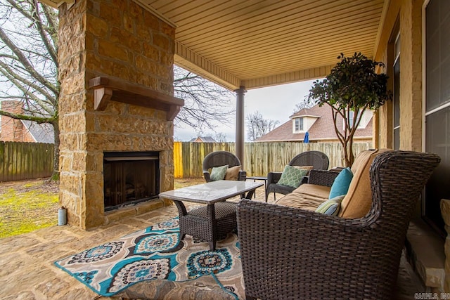 view of patio featuring an outdoor stone fireplace and a fenced backyard