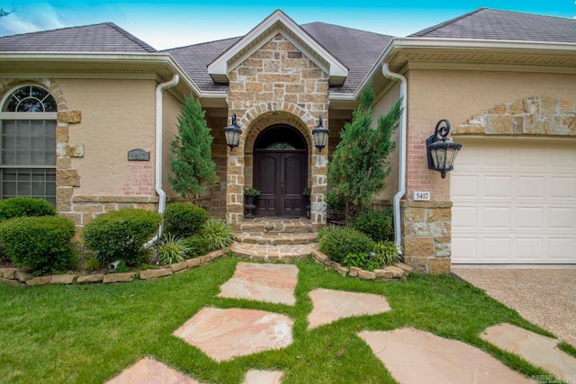 doorway to property with an attached garage, stone siding, and stucco siding