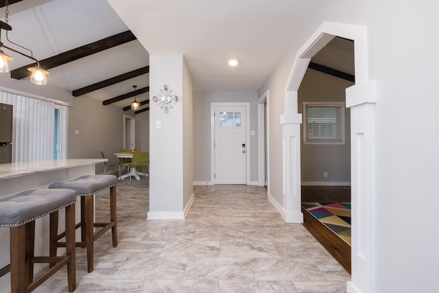 foyer with arched walkways, beamed ceiling, and baseboards